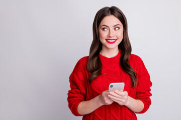 Photo portrait of curious girl keeping smartphone looking at blank space isolated on pastel grey...