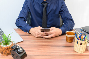 Fototapeta na wymiar Businessmen use smartphones at their desks in the room.