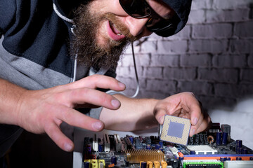 Bearded hacker in sunglasses and hoodie cracking the hardware