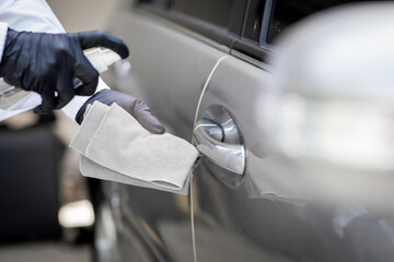 Car disinfecting service. Woman disinfecting and cleaning the inside handle of the car door. Safety and preventing infection of Covid-19 virus, contamination of germs or bacteria, wipe clean surfaces