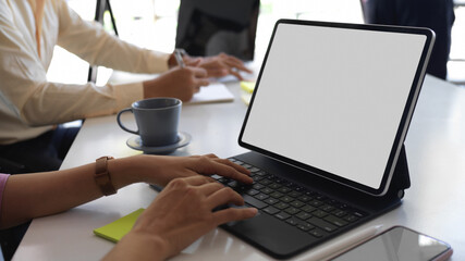 Fototapeta premium Hands typing on tablet keyboard on meeting table in office room