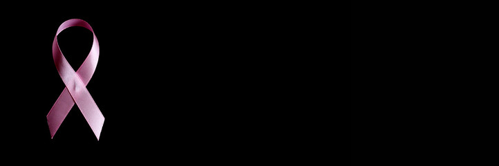 pink ribbon, a symbol of breast cancer awareness, isolated on a black background. space for text....