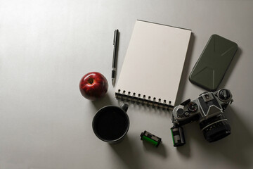 Workspace with blank notebook, camera, supplies and copy space on white desk