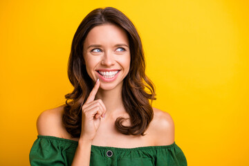 Photo of happy dreamy young woman hold finger chin smile look empty space isolated on yellow color background