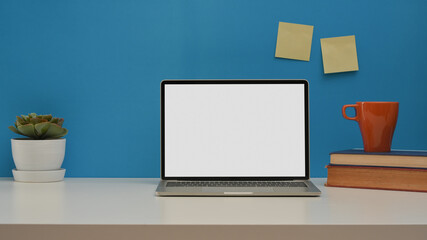 Home office desk with laptop, books, mug, plant pot and copy space