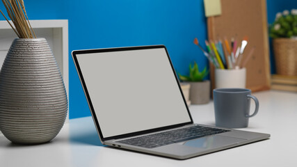 Side view of worktable with laptop, stationery, decorations in home office room