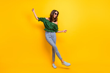 Obraz premium Full body photo of careless pretty joyful young woman raise hands dancer wear glasses isolated on yellow color background
