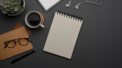 Worktable with blank notebook, coffee cup, glasses, supplies and copy space on the table