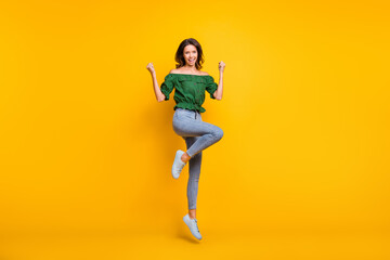 Fototapeta na wymiar Full body photo of victorious happy woman raise fists yeah jump up wear shoes isolated on shine yellow color background