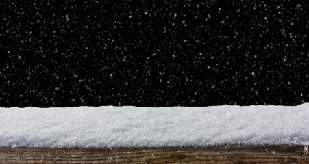 Empty wooden table snow covered with snowfall isolated on black background