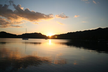 Beautiful peaceful bay view with sails, mountains, reflection on the sea and cloudy sky at sunset at Mediterranean Kas Antalya Turkey