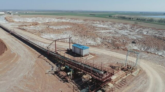 Mining of potash salt, conveyor line in salt pits, aerial view of salt piles and industrial quarries, view from height on hills of sand, sludge and mining waste.