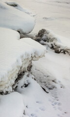 Icicles and frost on a snow-covered frozen river