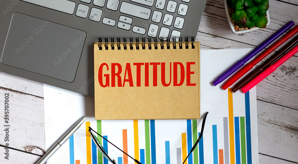 Poster gratitude text in notepad with a business objects and chart and laptop