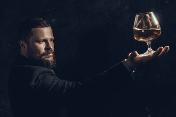 Solid confident bearded man in suit with glass of whisky