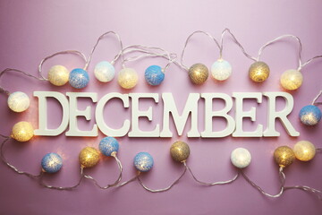 December alphabet letter with cotton ball LED decoration on purple background