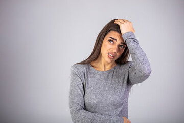 Portrait of beautiful young brunette touching her temples feeling stress, on gray background. Young beautiful woman has headache, isolated on gray background