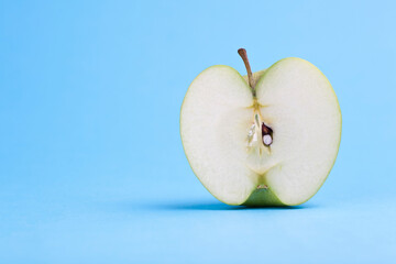 Half cut green apple. Studio photo isolated on blue background. Selective focus on object.