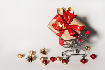 Shopping cart with gift box and christmas toys balls. Christmas shopping gifts concept