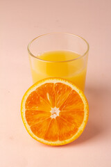 orange juice and orange slice on pink background and space for text.