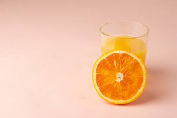 orange juice and orange slice on pink background.