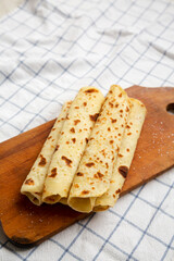 Homemade Norwegian Potato Flatbread (Lefse) with Butter and Sugar on a rustic wooden board on cloth, side view. Copy space.