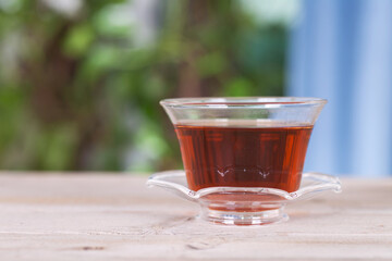 There is a bowl of hot black tea on the indoor table