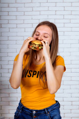 a girl eats a Burger in a yellow t-shirt