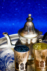 Group of teapot and glasses of oriental tea on a tray on blue background with glitter