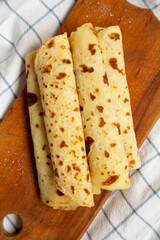 Homemade Norwegian Potato Flatbread (Lefse) with Butter and Sugar on a rustic wooden board on cloth, top view. Overhead, from above, flat lay.