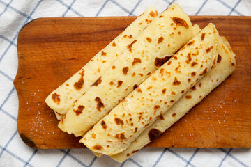 Homemade Norwegian Potato Flatbread (Lefse) with Butter and Sugar on a rustic wooden board on cloth, top view. Overhead, from above, flat lay. Close-up.