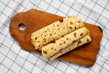 Homemade Norwegian Potato Flatbread (Lefse) with Butter and Sugar on a rustic wooden board on cloth, overhead view. Top view, flat lay.