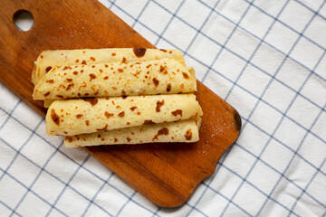 Homemade Norwegian Potato Flatbread (Lefse) with Butter and Sugar on a rustic wooden board on cloth, overhead view. Top view, flat lay. Copy space.