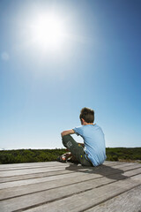 Boy Sitting On Boardwalk