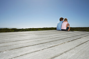 Girl And Boy Sitting On Boardwalk