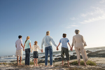 Three Generation Family Holding Hands On Seashore - Powered by Adobe