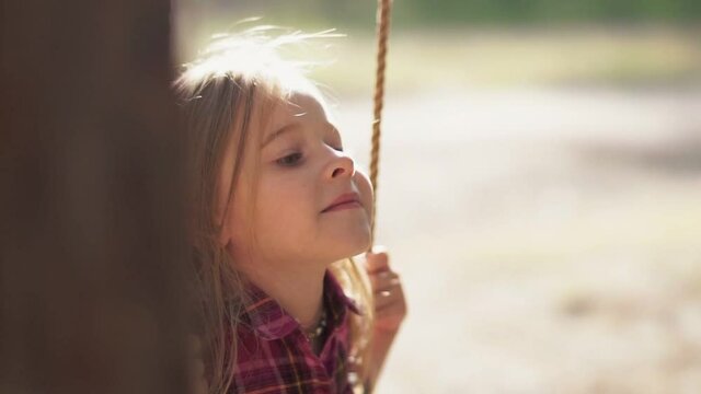 Girl swinging on a swing in the park between&nbsp;trees.