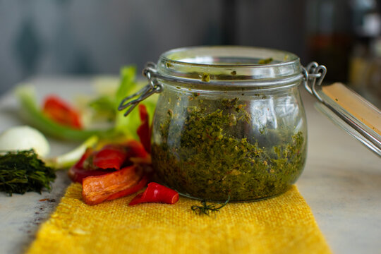 Spicy and hot adjika sauce in a round glass jar prepared from red hot chili pepper, dill, garlic and other ingredients
