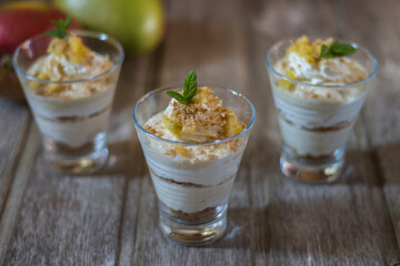 Mango mousse in glass cup with mint on wooden background