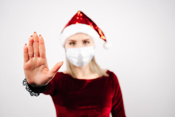Fototapeta na wymiar A girl in a medical mask and a Santa hat, points a finger. New Year's and Christmas