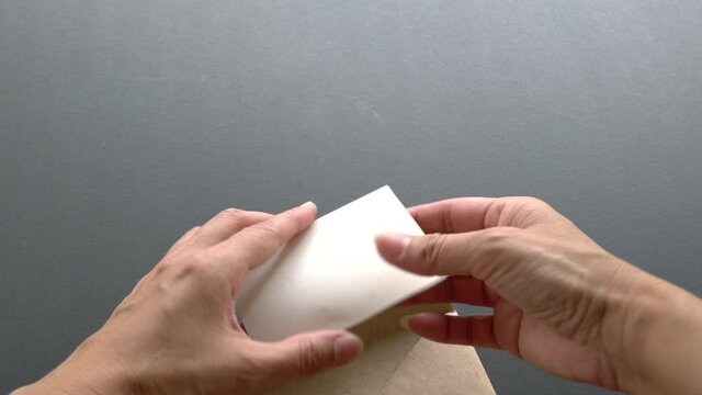 Woman open an envelope to find a card or note with the words, Good News. Close up shot.
