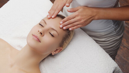 Young, beautiful and healthy woman in massaging salon. Traditional face massage therapy and skin care.