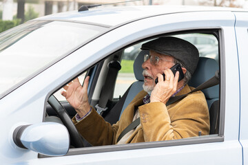 Old man drives his car while talking on mobile phone. Dangerous driving on the road