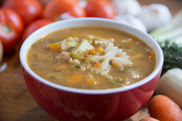 Minestrone soup, a typical thick vegetables soup, originally from Italy, served in a red bowl with Farfalle Pasta. 