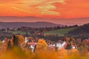 Die Dorfkirche zwischen Häusern und herbstlich gefärbten Bäumen nach Sonnenuntergang fotografiert