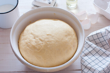 Freshly cooked yeast dough in ceramic bowl on white wooden table, selective focus