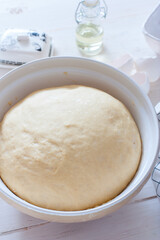 Freshly cooked yeast dough in ceramic bowl on white wooden table, selective focus
