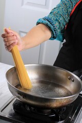 Women Cooking Spaghetti in Pan of Boiling Water in the Kitchen. Home Cooking Process and Preparation