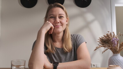 blonde woman in gray t-shirt communicates online from home with her family and say Hello to them....