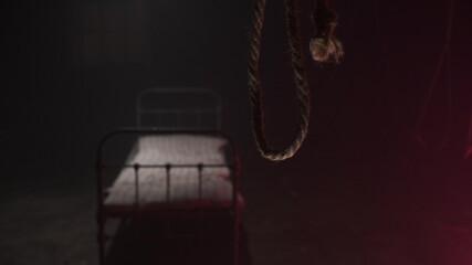 scary noose gallows for execution swings in dark against background of white metall bed in dark...